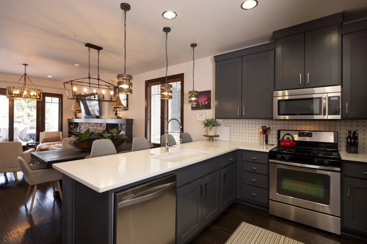 A spacious kitchen scene with a central island, modern stainless steel appliances, pendant lighting, and an adjacent dining area. The open layout is designed for both cooking and entertaining, with ample space for family and friends to gather and interact.
